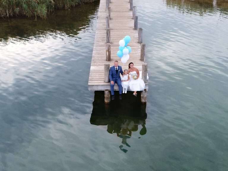 A Couple On The Edge Of A Boat Wharf On Their Wedding Day